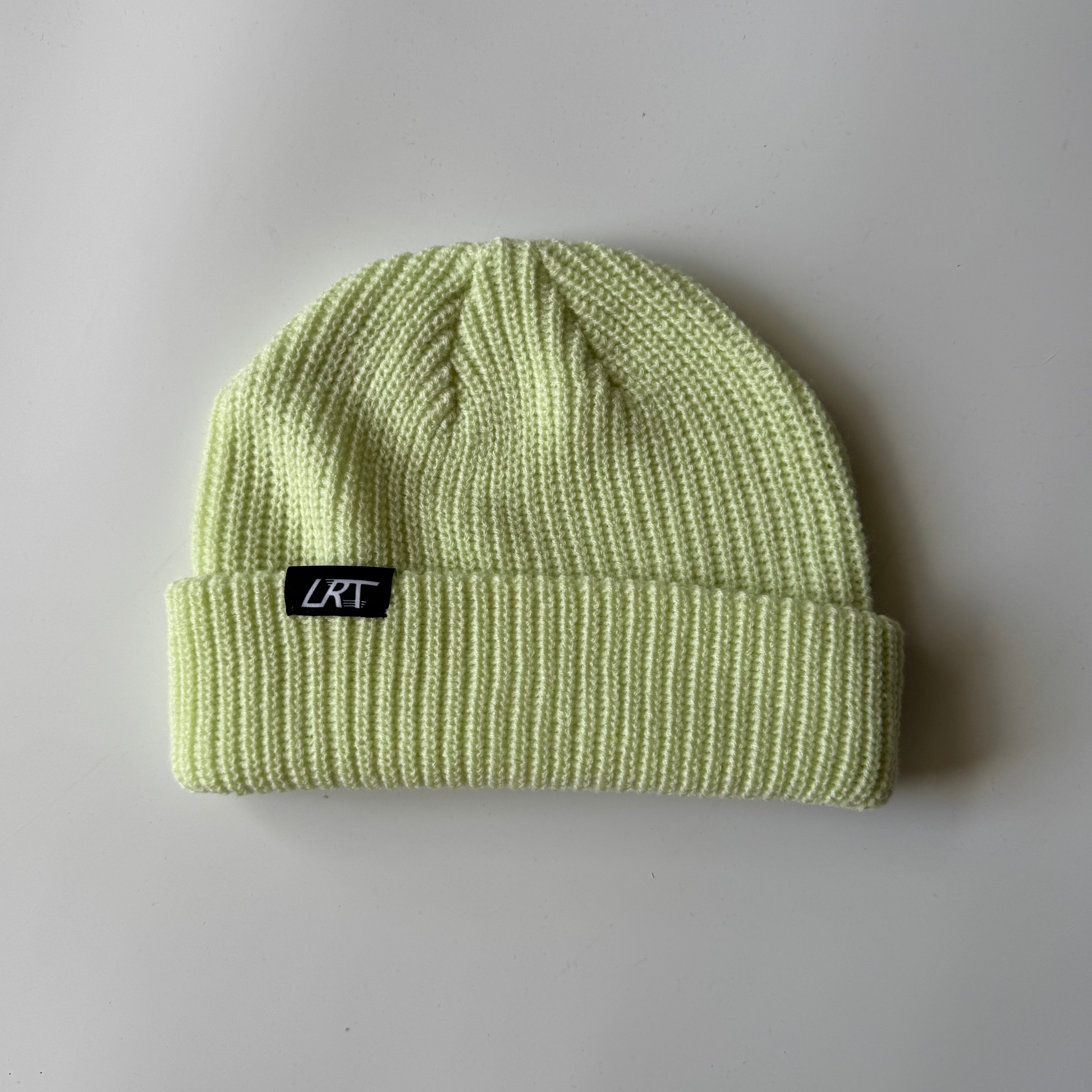 Light green beanie with a black label on a gray background
