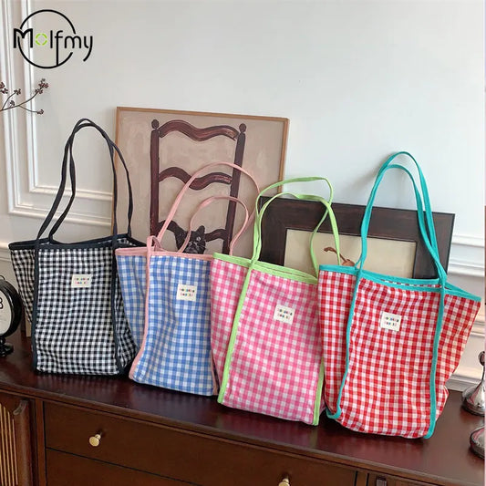 Four gingham checkered bags in different colors on a wooden surface with a neutral background.